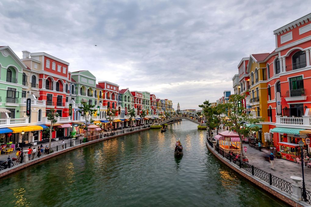 Un colorido canal bordeado de edificios y cafés, con un barco en el agua bajo un cielo nublado.