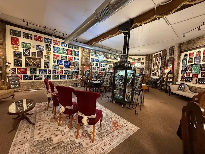 An art gallery interior with framed art, a sitting area, and display cases.