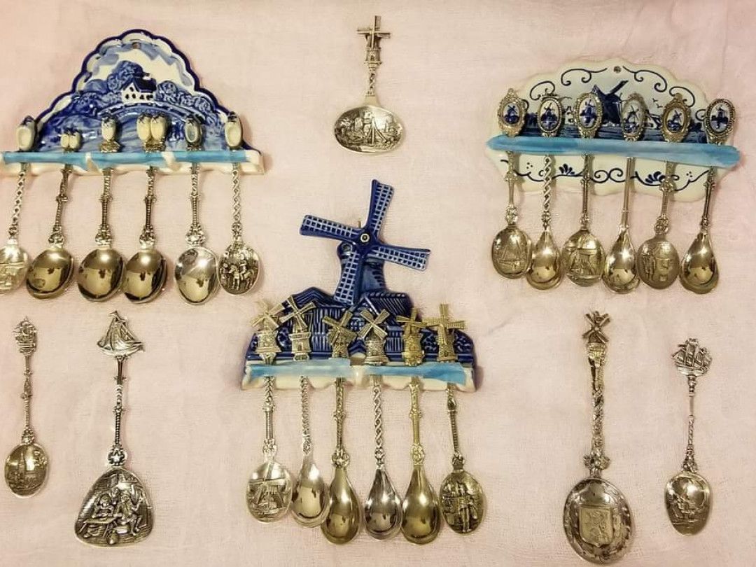 Collection of Dutch souvenir spoons hanging on blue and white ceramic holders.