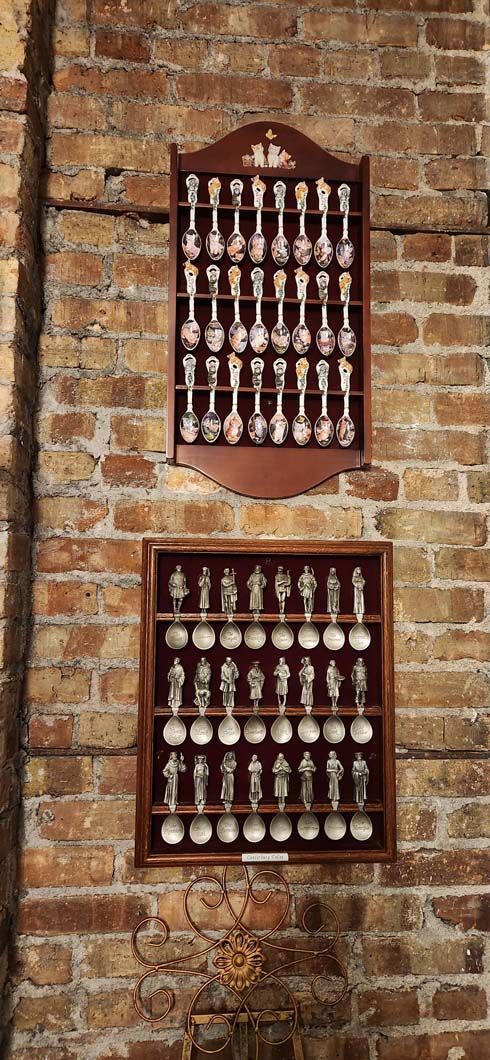 Two wooden display cases holding spoons on a brick wall.