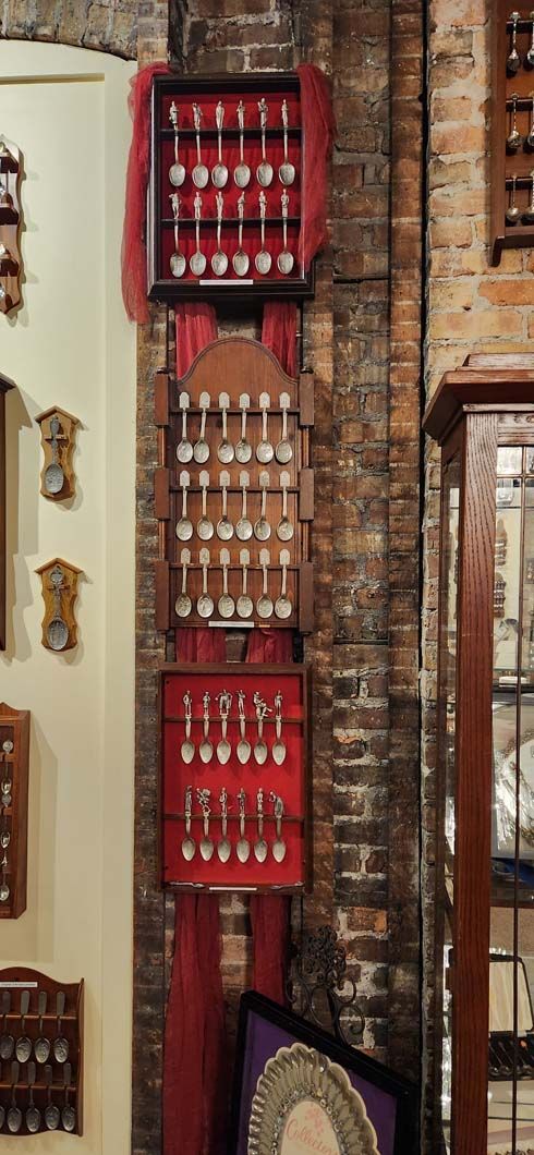 Wooden display cases with silverware on a brick wall, with red velvet accents.