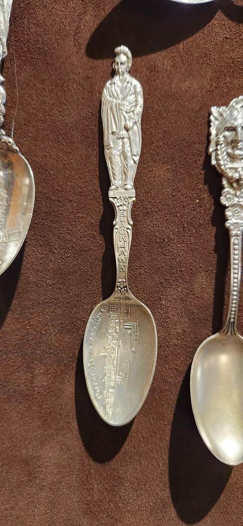 A silver spoon with a figure on the handle.