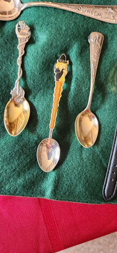 Three ornate spoons on a green and red cloth.