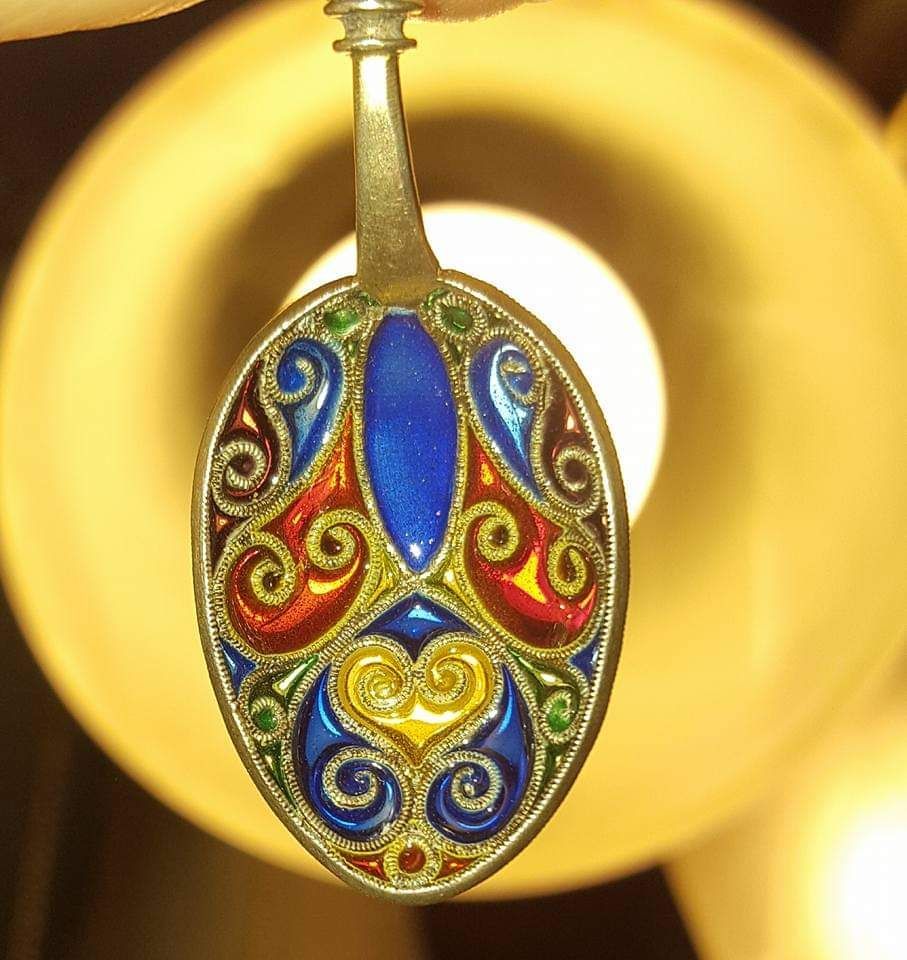 Ornate, colorful enamel spoon pendant with blue, red, yellow, and green swirls.