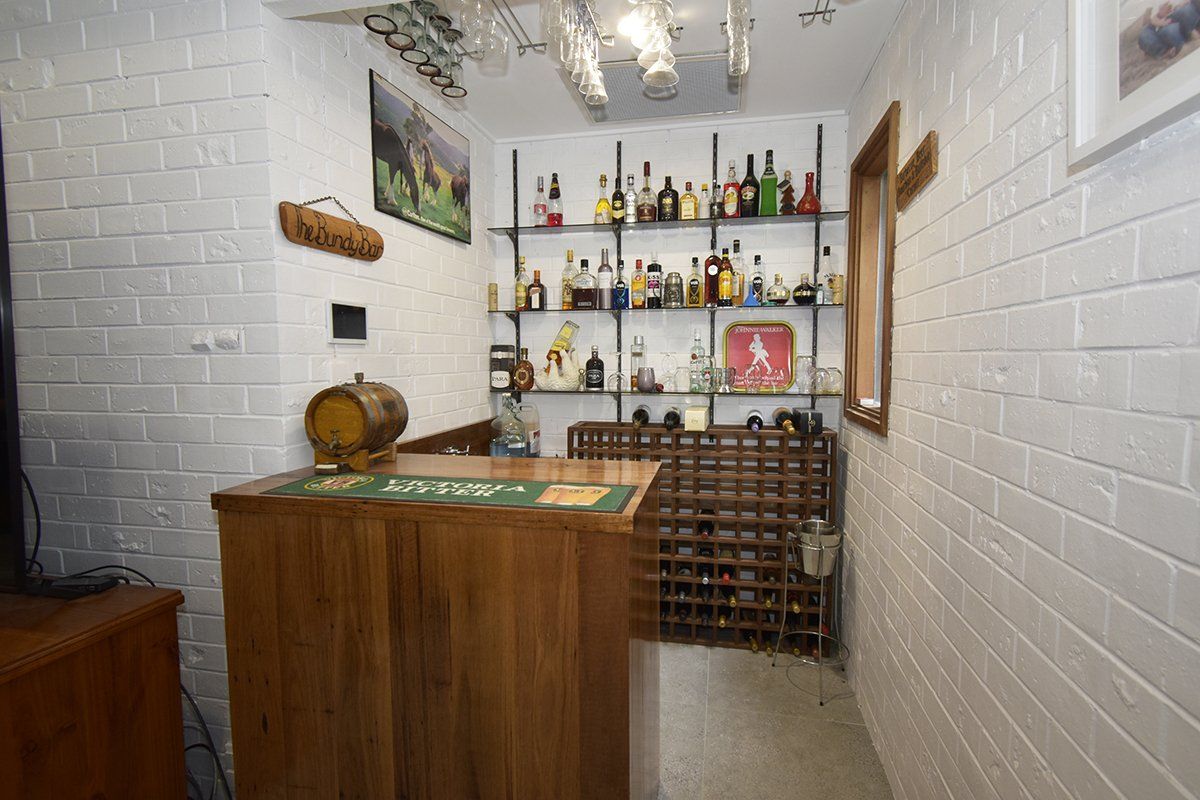 A small room with a bar and shelves filled with bottles of alcohol.