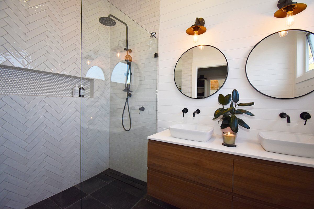 A bathroom with two sinks and a walk in shower.