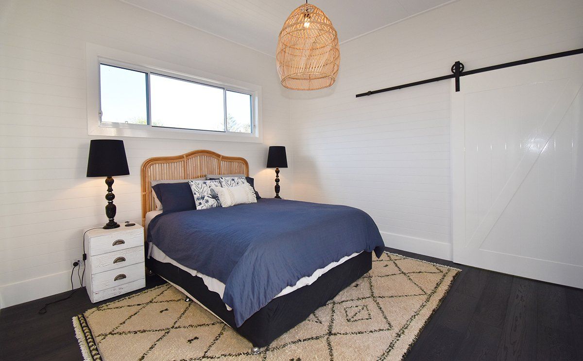 A bedroom with a bed, nightstands, lamps and a sliding barn door.