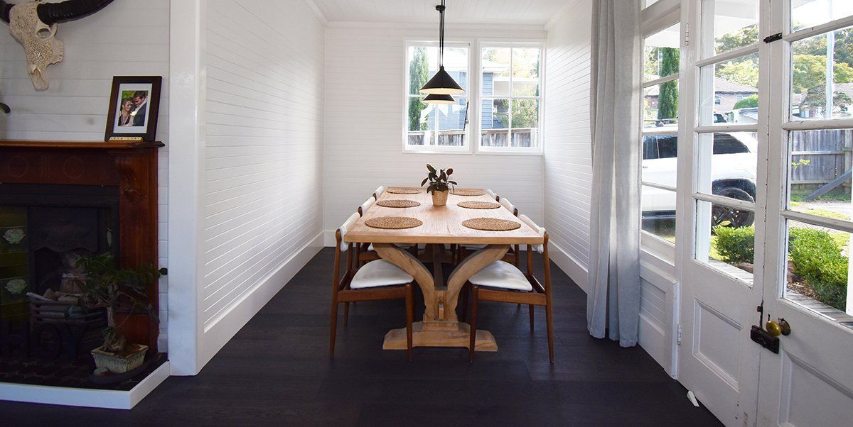 A dining room with a long table and chairs and a fireplace.