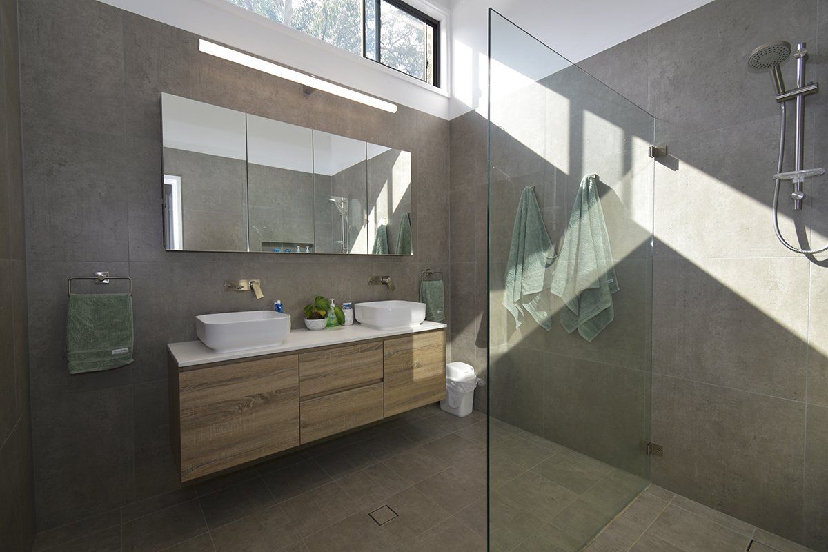 A bathroom with two sinks and a walk in shower.