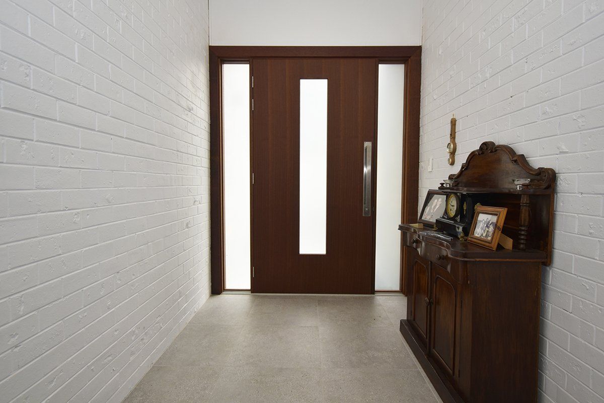 A hallway with a wooden door and a dresser with pictures on it.