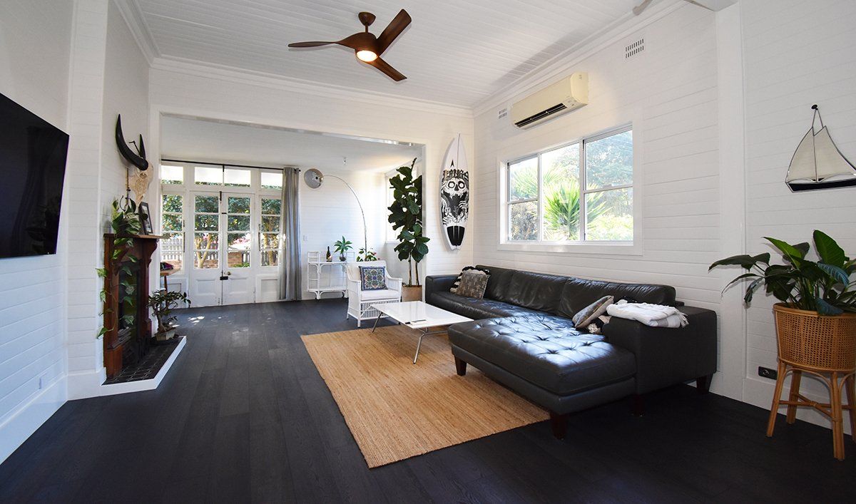 A living room with a black couch and a ceiling fan