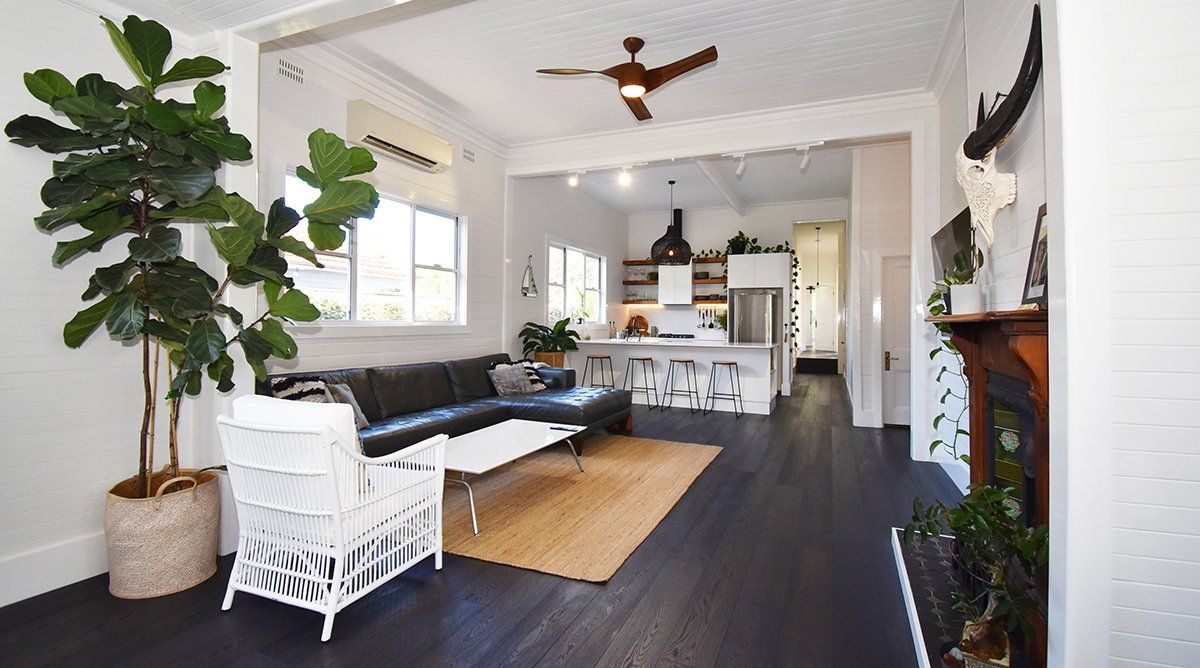 A living room with a couch, chair, table and ceiling fan.