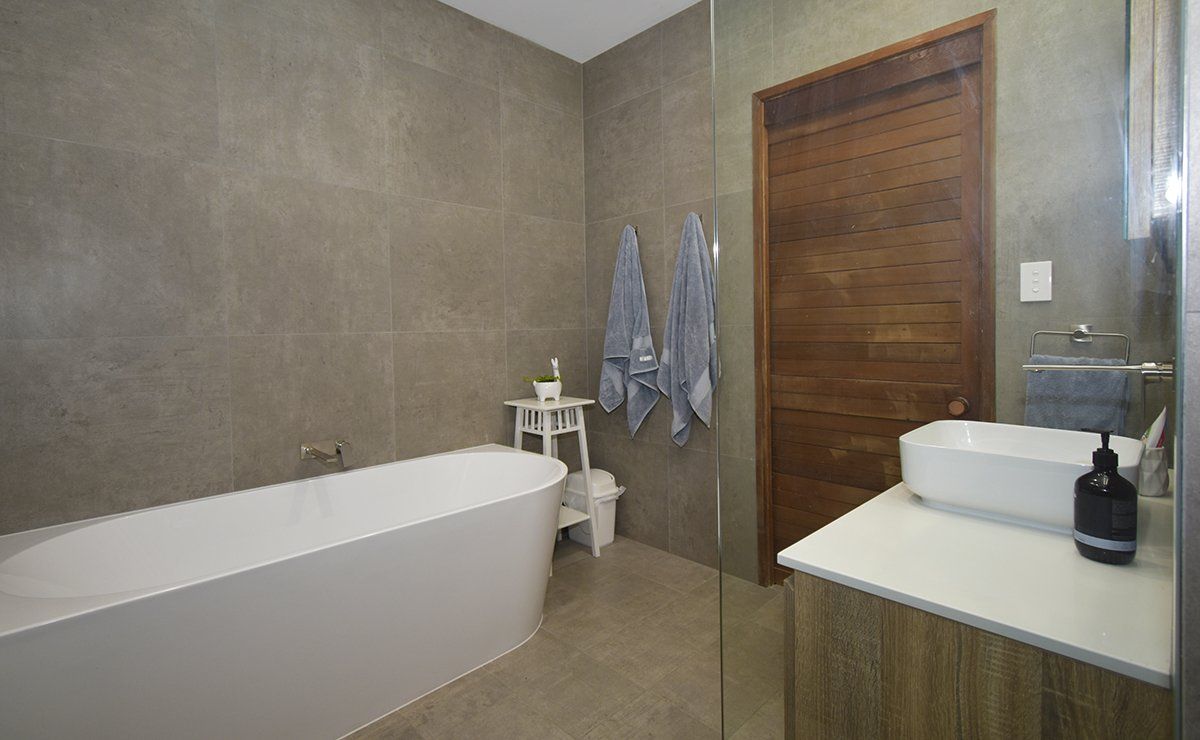 A bathroom with a bathtub , sink and mirror.
