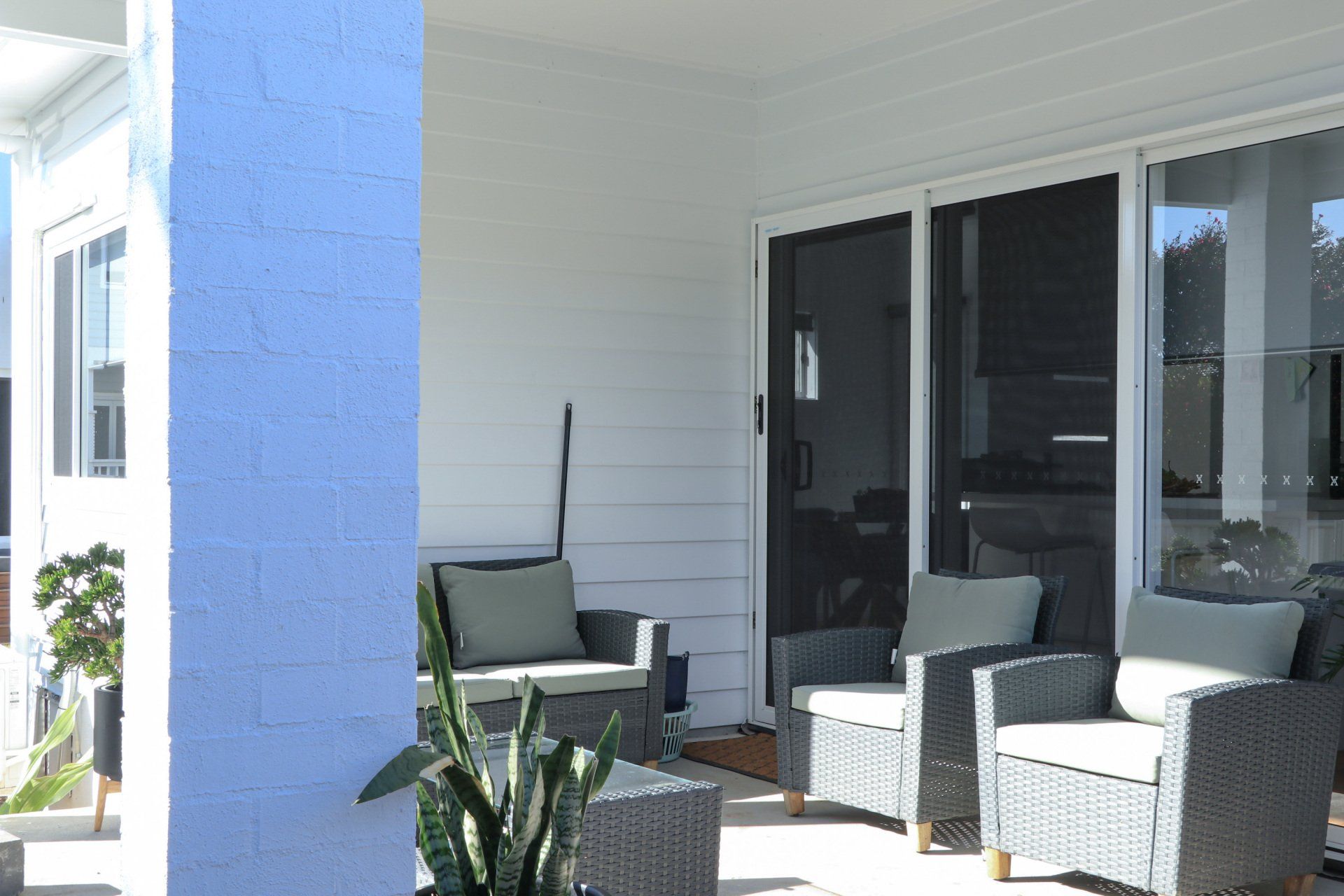 A porch with chairs and a couch and a plant