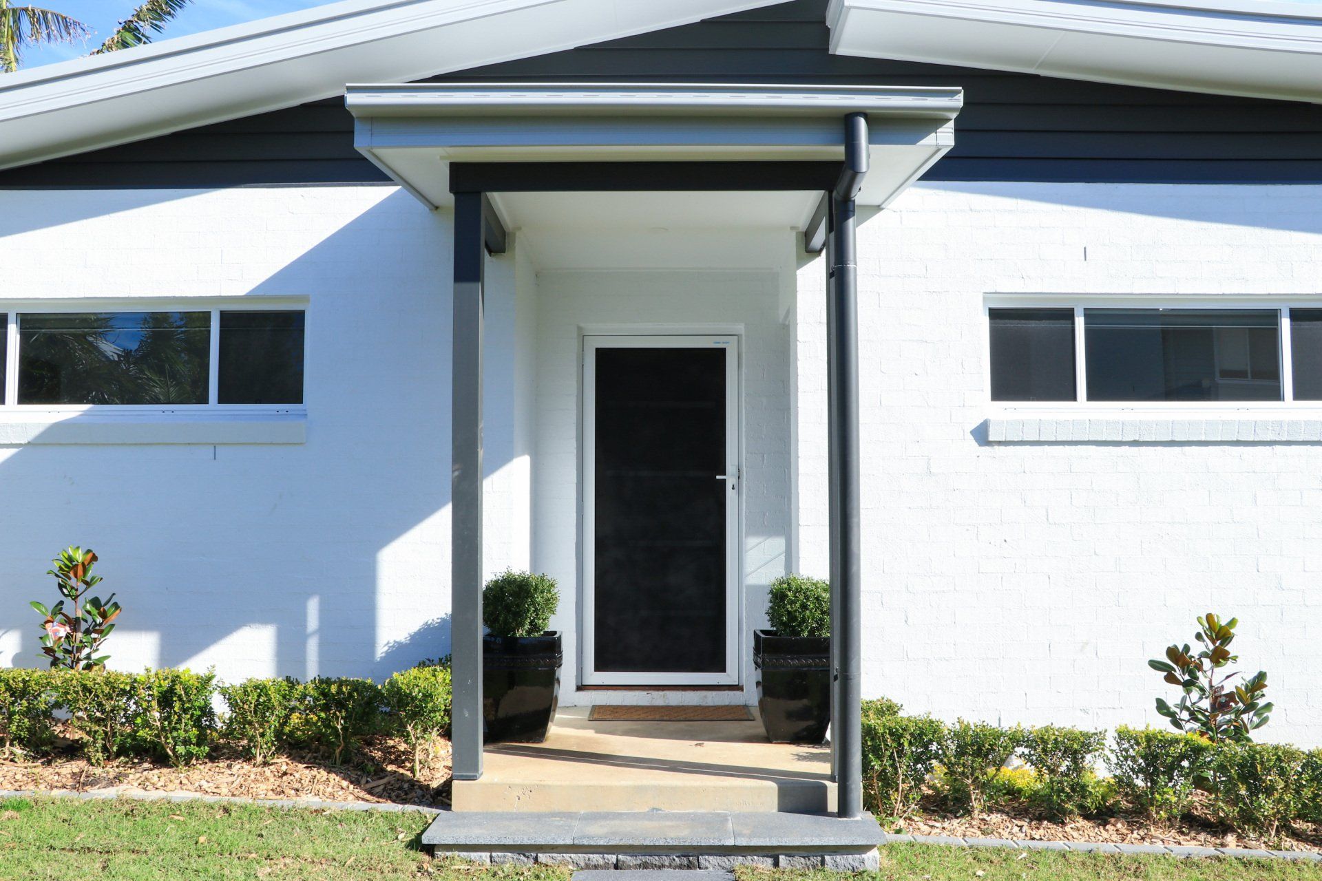 A white house with a black door and a porch