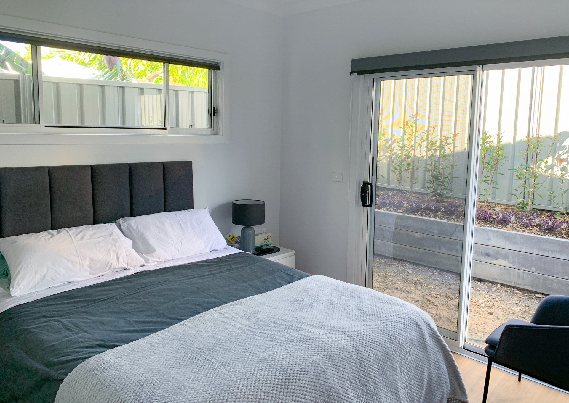 A bedroom with a king size bed and a sliding glass door leading to a patio.