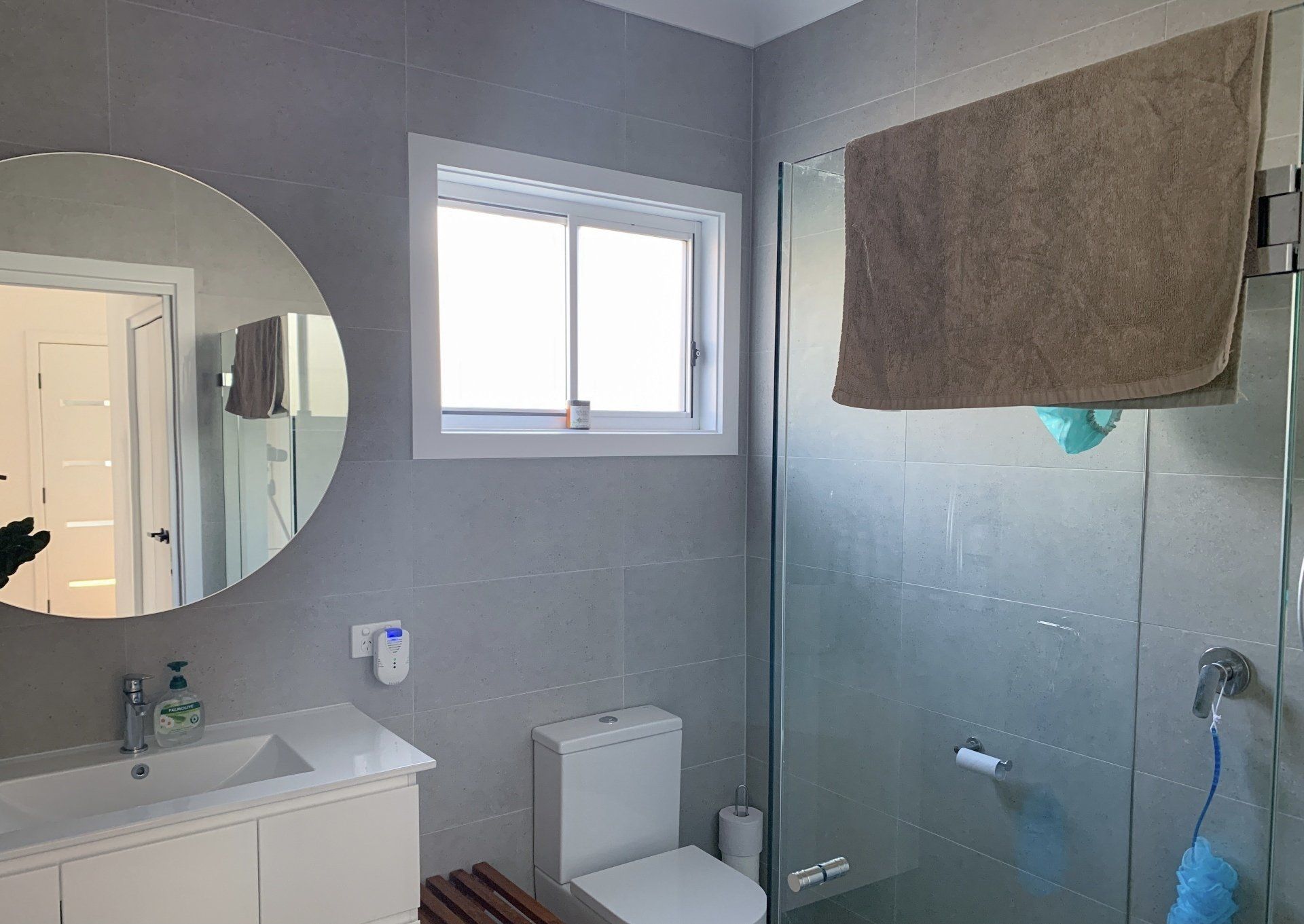 A bathroom with a toilet , sink , mirror and shower.