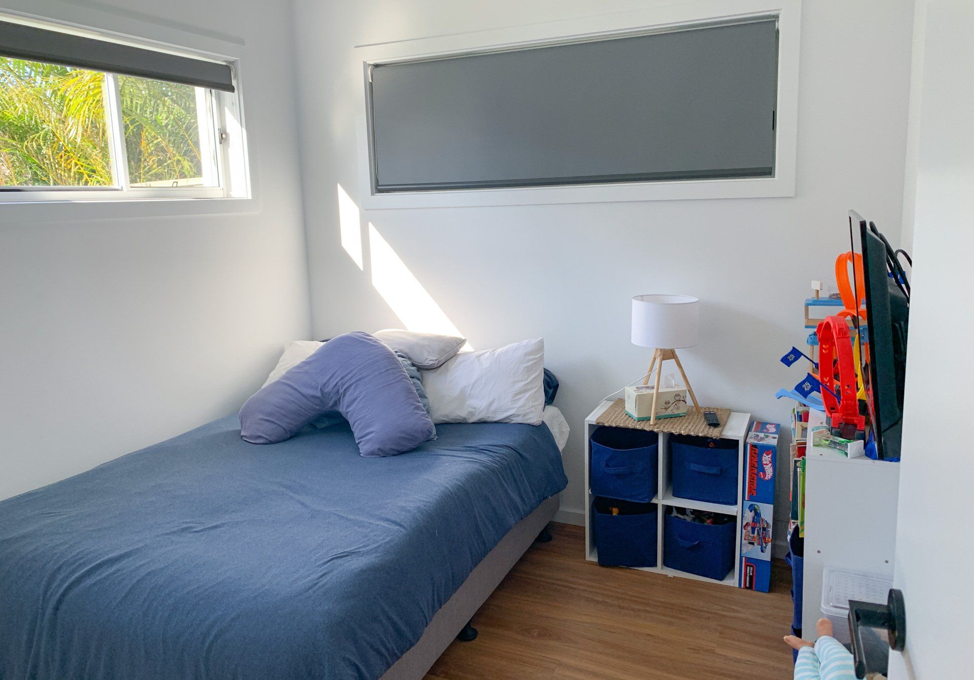 A bedroom with a bed, nightstand, lamp and window.