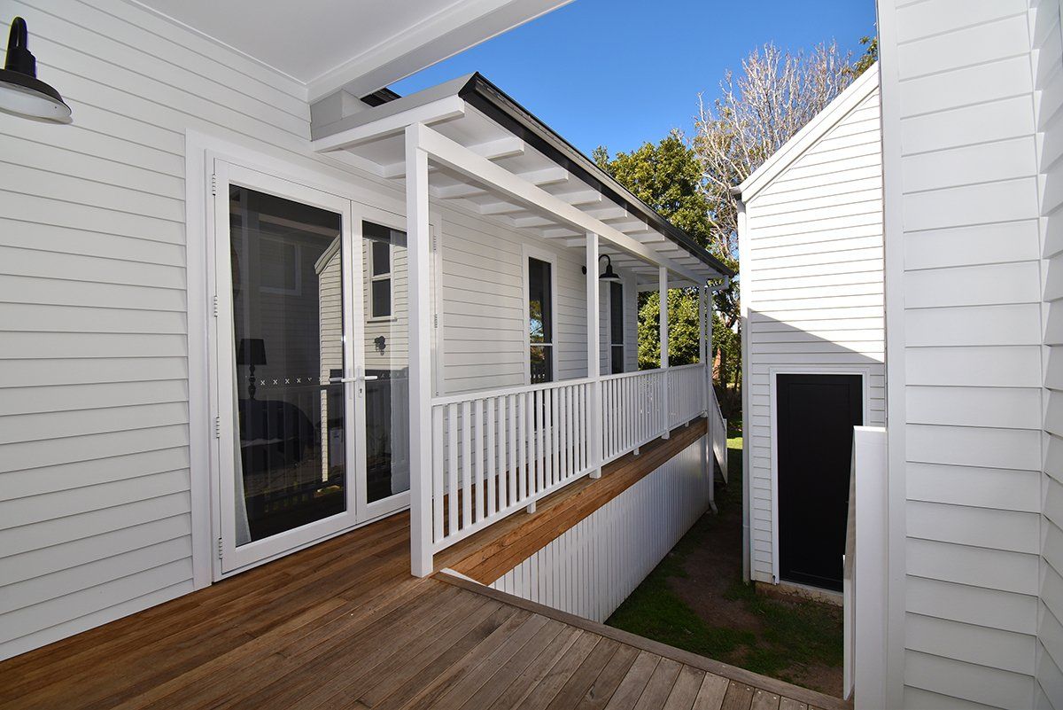 A white house with a porch and a wooden deck
