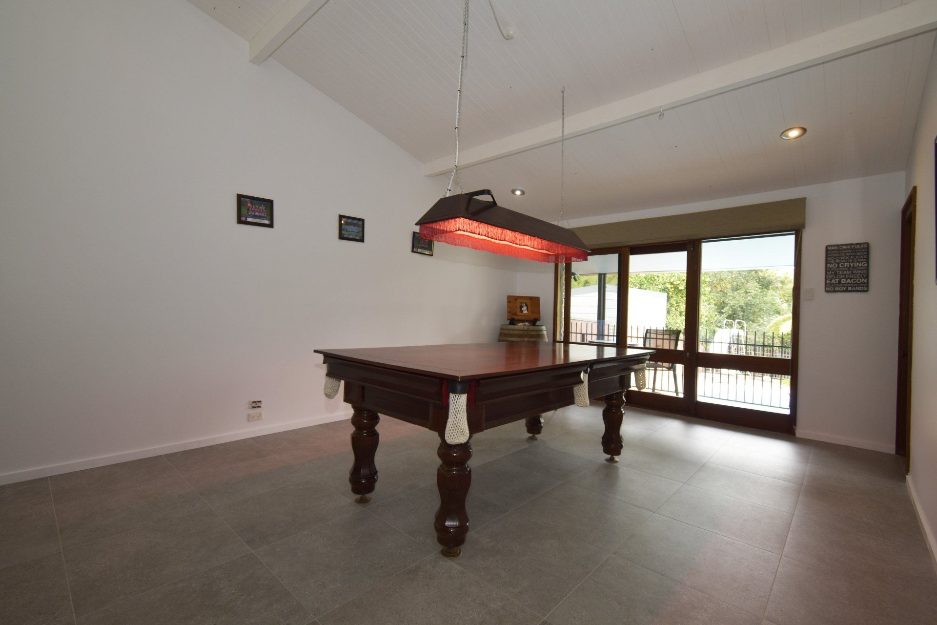 A pool table in a room with a red light hanging from the ceiling