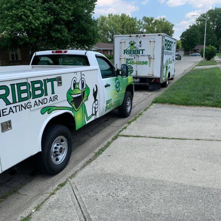 Ribbit Heating and Air service trucks parked along a sidewalk in a suburban street.