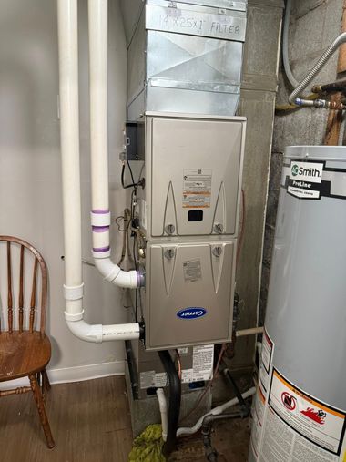 Furnace and water heater in a utility closet with white pipes and a silver vent duct