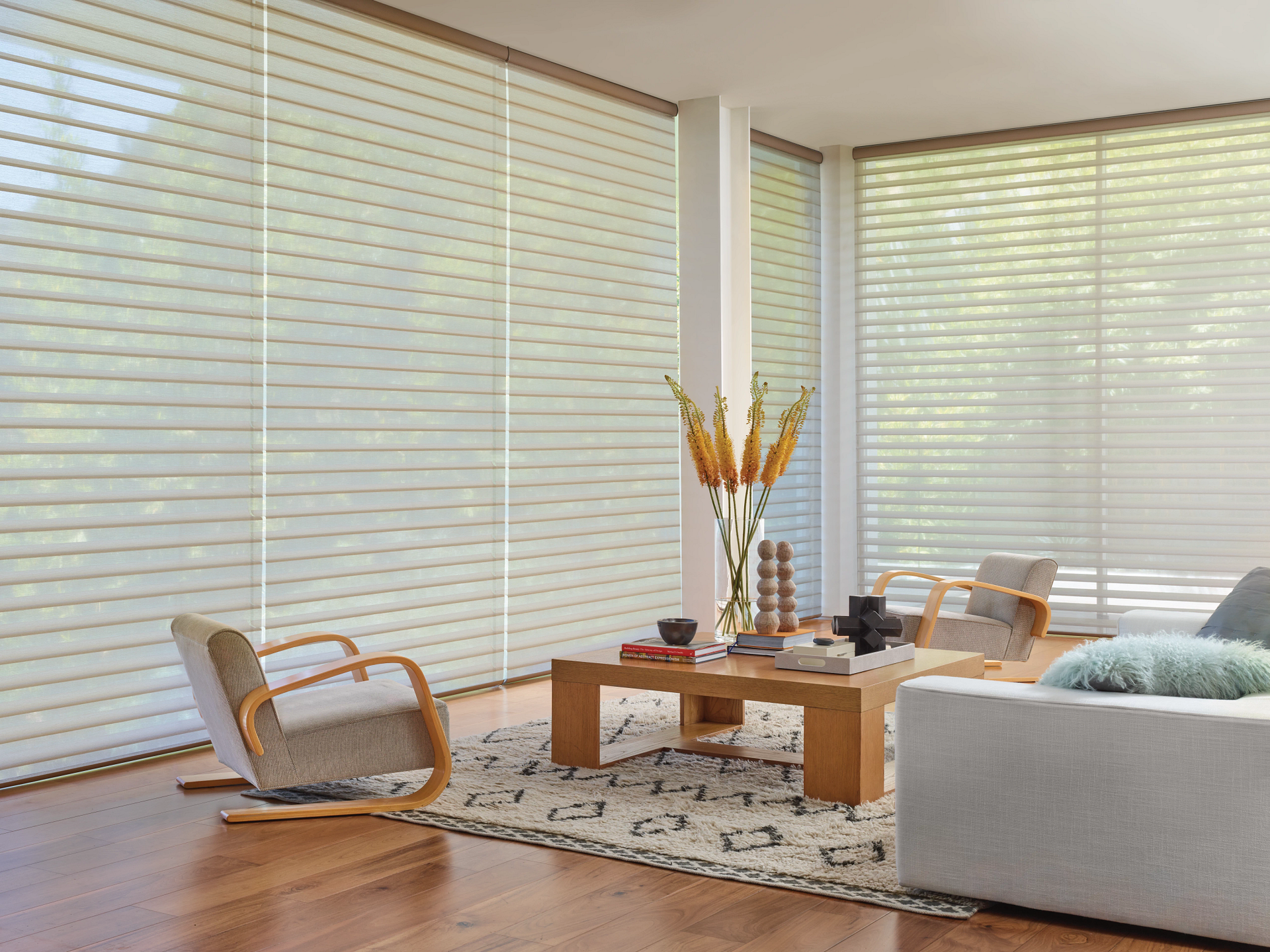 Motorized window shades covering multiple windows in a living room.