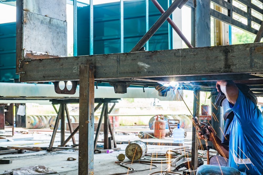 A Man Is Welding A Metal Structure In A Factory — BM Steel Fabrication In Nabiac, NSW
