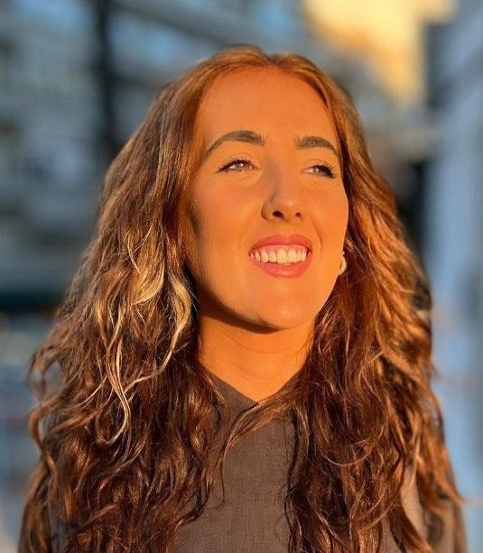 A woman with long brown hair is smiling for the camera.