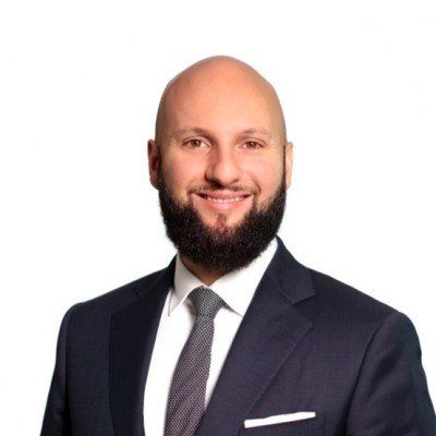 A bald man with a beard is wearing a suit and tie.