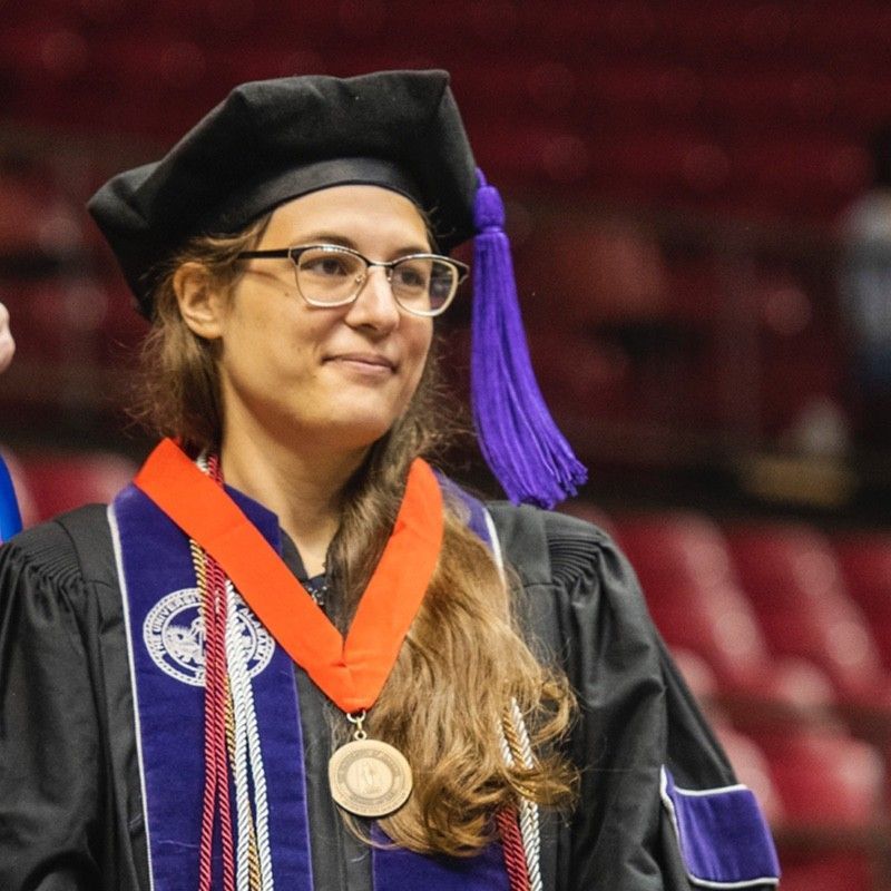 A woman in a graduation cap and gown with a medal around her neck