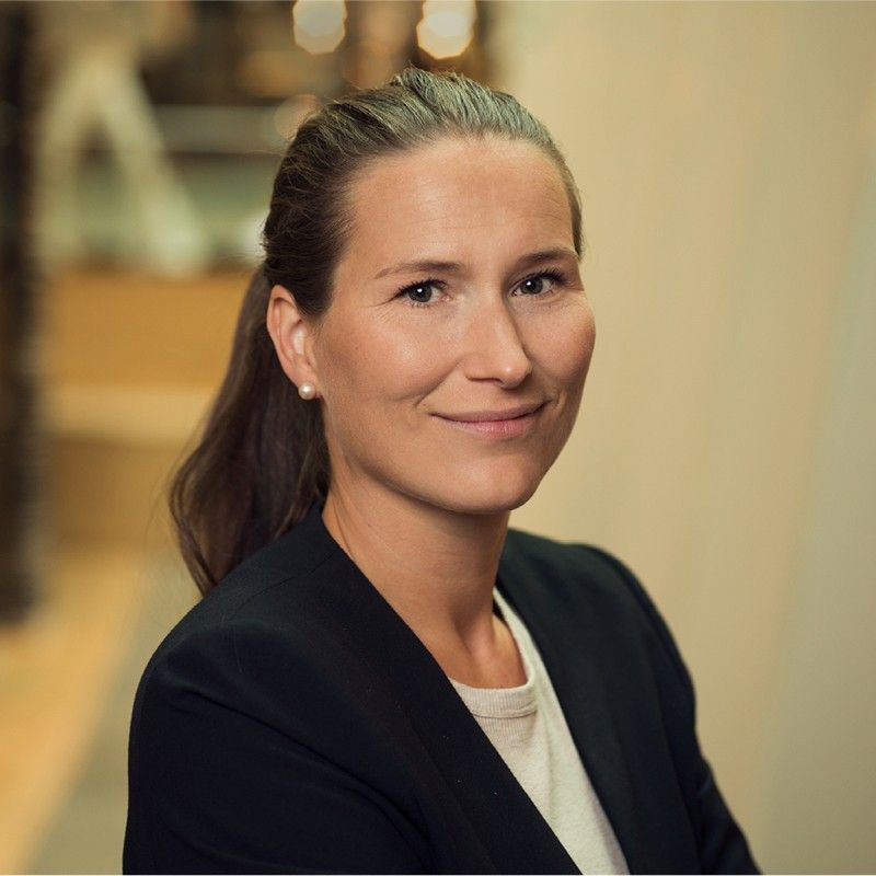 A woman in a black jacket and white shirt smiles for the camera