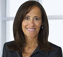 A woman in a black jacket is smiling for the camera.