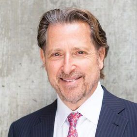 A man in a suit and tie is smiling for the camera.