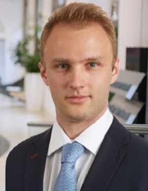 A man in a suit and tie is standing in an office.