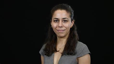 A woman is smiling in front of a black background.