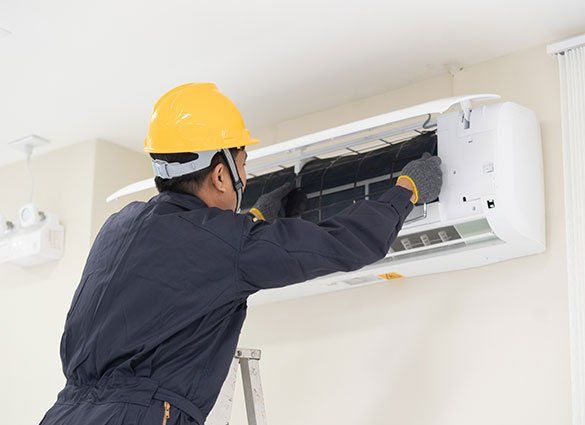 Worker Cleaning Air Conditioner — Honolulu, HI — Air Conditioning Experts Worker Cleaning Air Conditioner — Honolulu, HI — Air Conditioning Experts