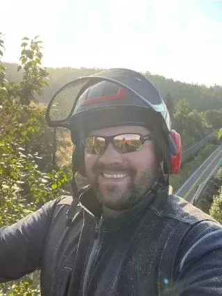 A man wearing a helmet and sunglasses is smiling for the camera