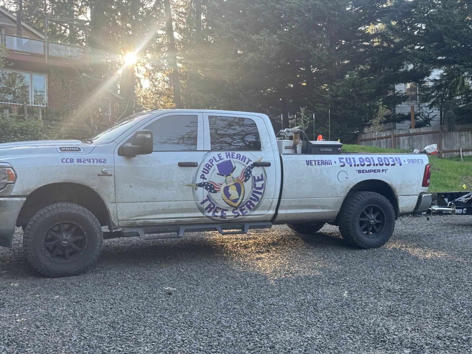 White pickup truck with business logo parked on gravel.