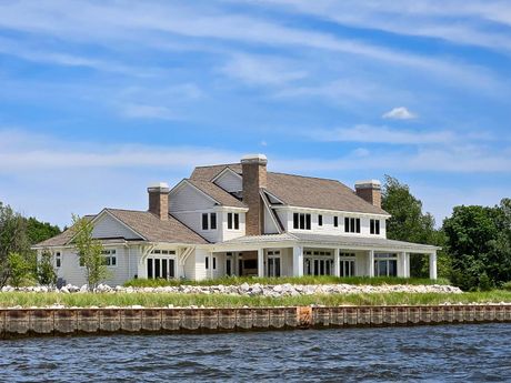 A large white house sits next to a body of water.