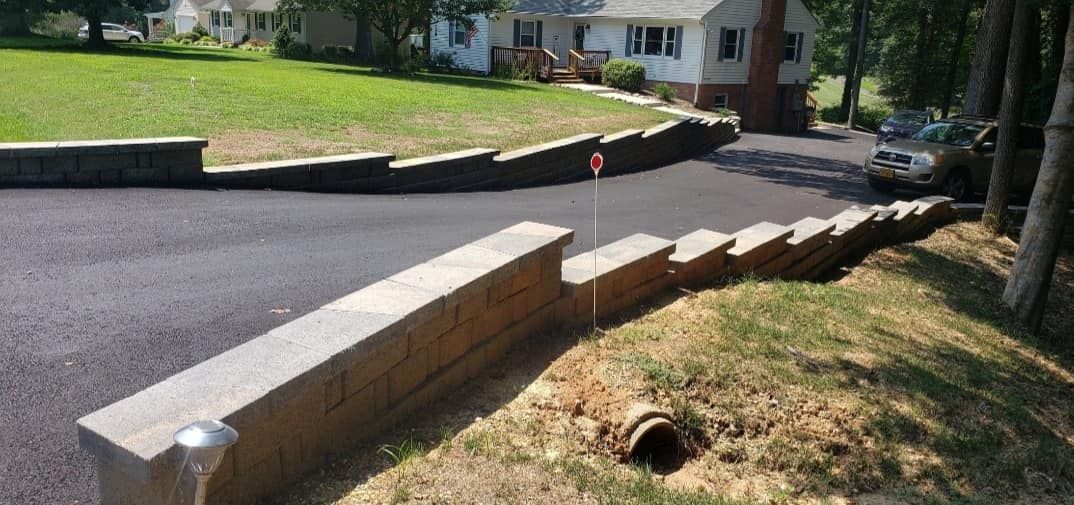 A brick wall along the side of a road next to a house.
