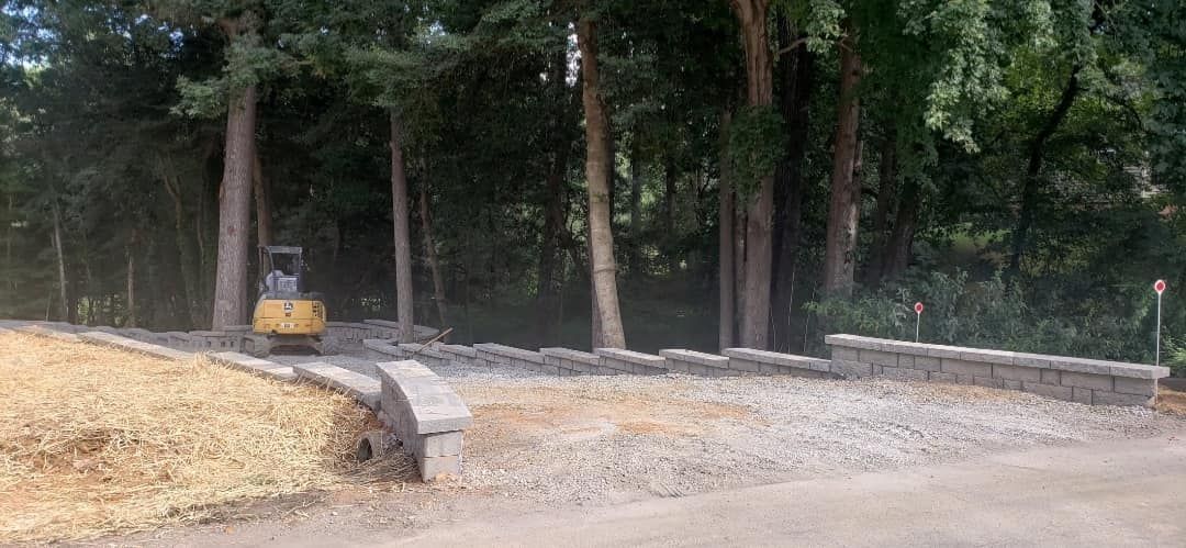 A bulldozer is driving down a dirt road in the woods.