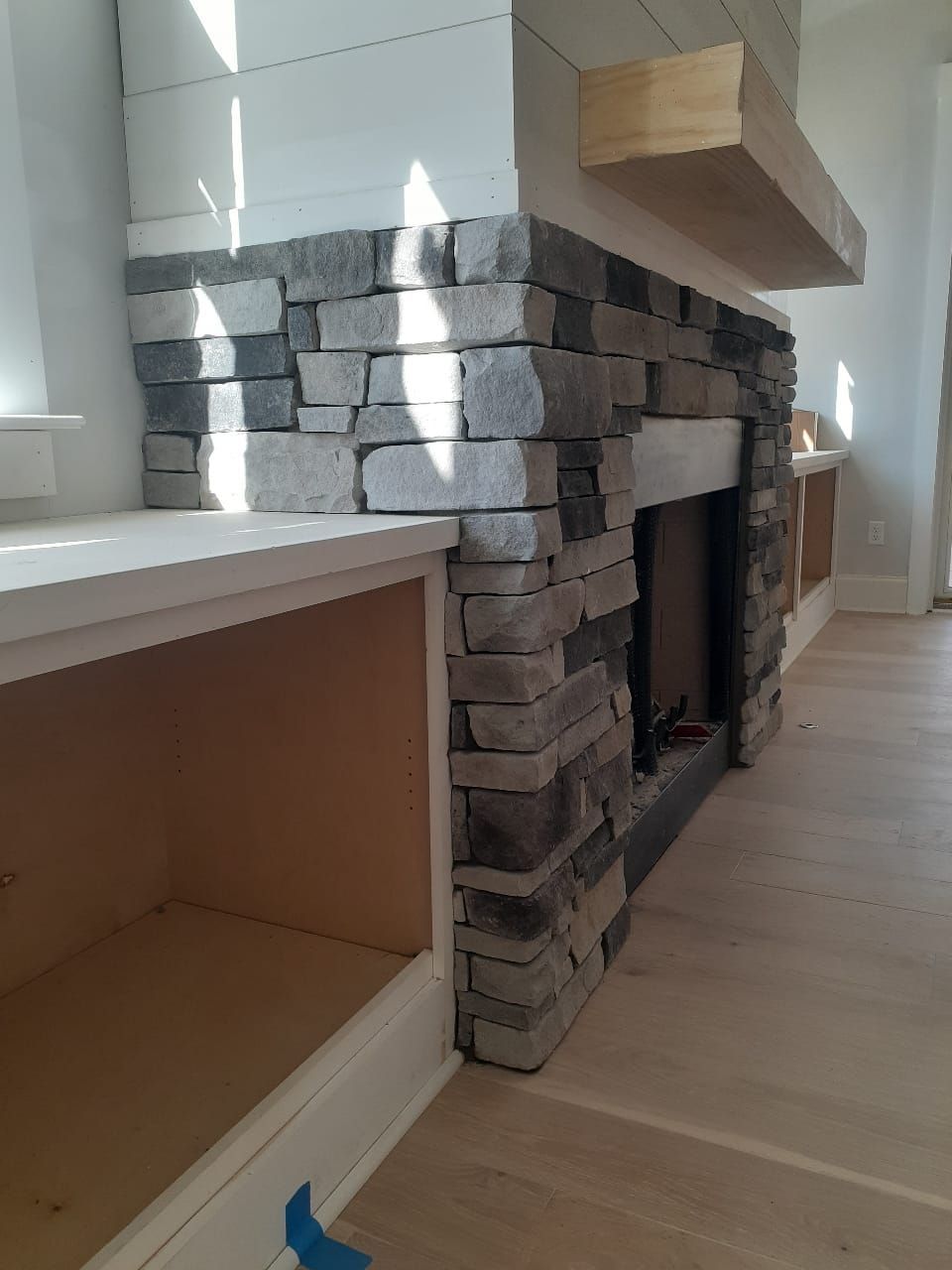 A stone fireplace is being built in a living room.