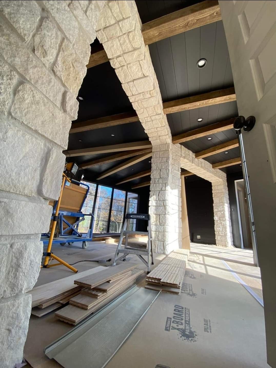 A room with a brick wall and wooden beams is being remodeled.