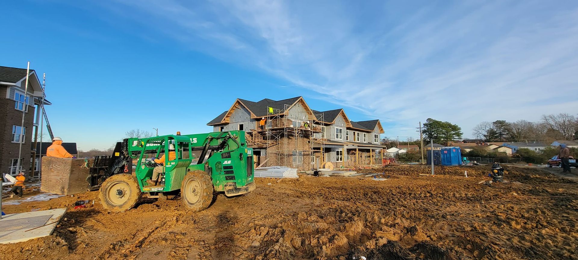 A large house is being built in the middle of a dirt field.