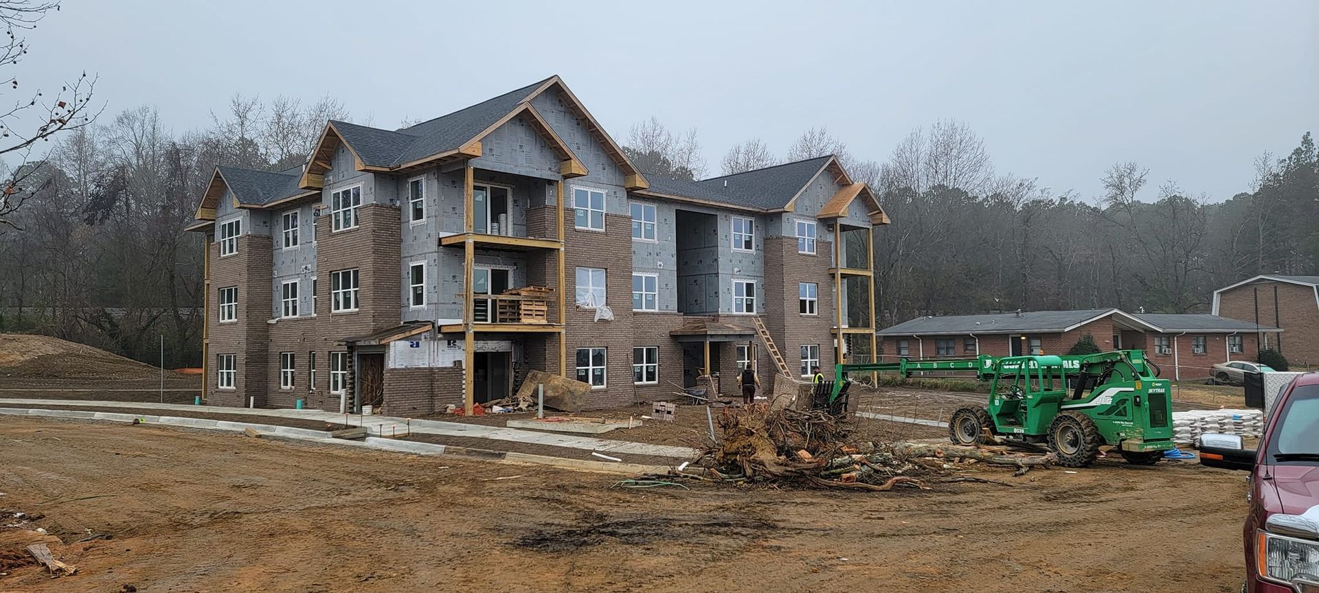 A large apartment building is being built in the middle of a dirt field.