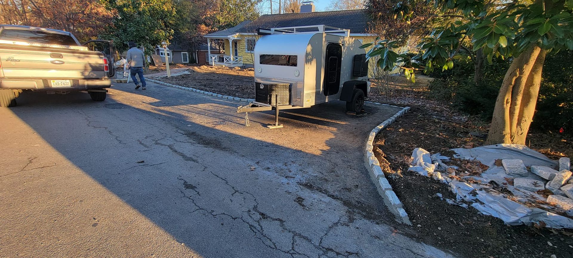 A trailer is parked on the side of the road next to a house.