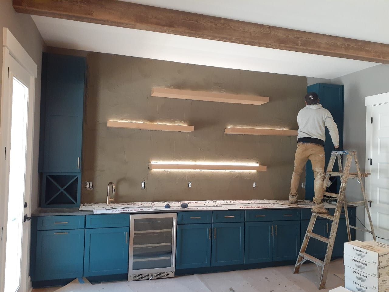 A man is standing on a ladder in a kitchen.