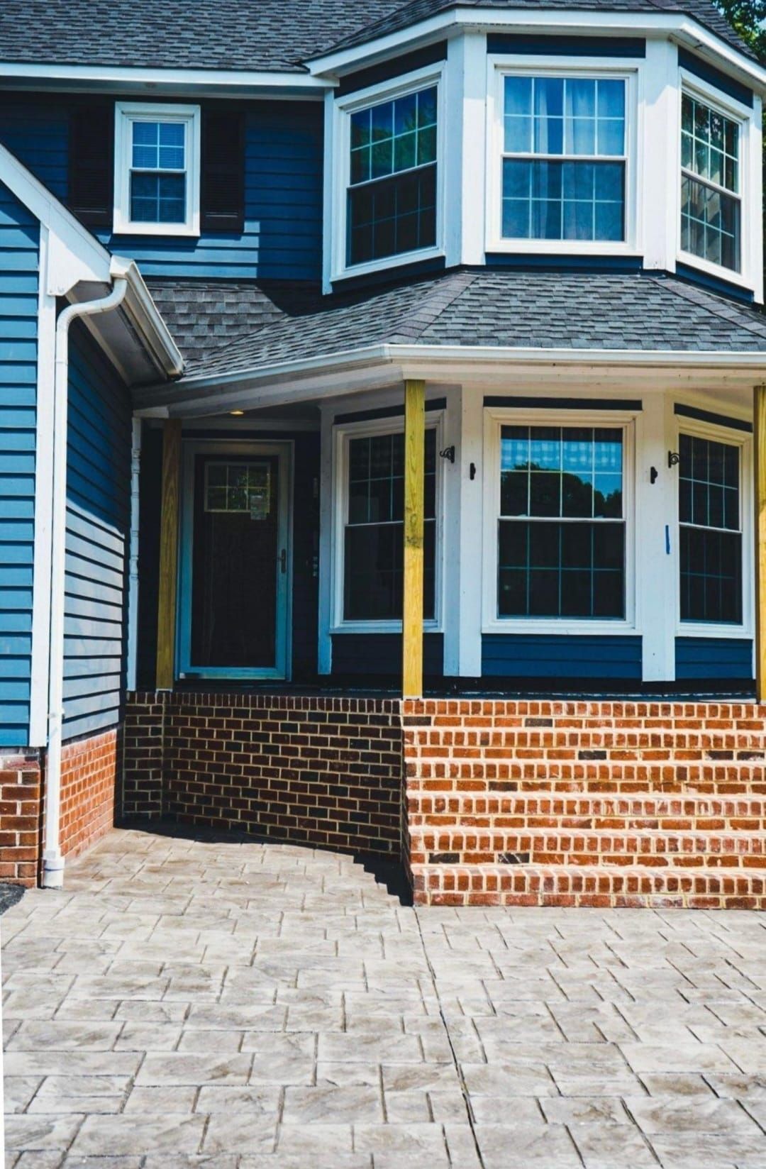 A blue house with a brick porch and stairs