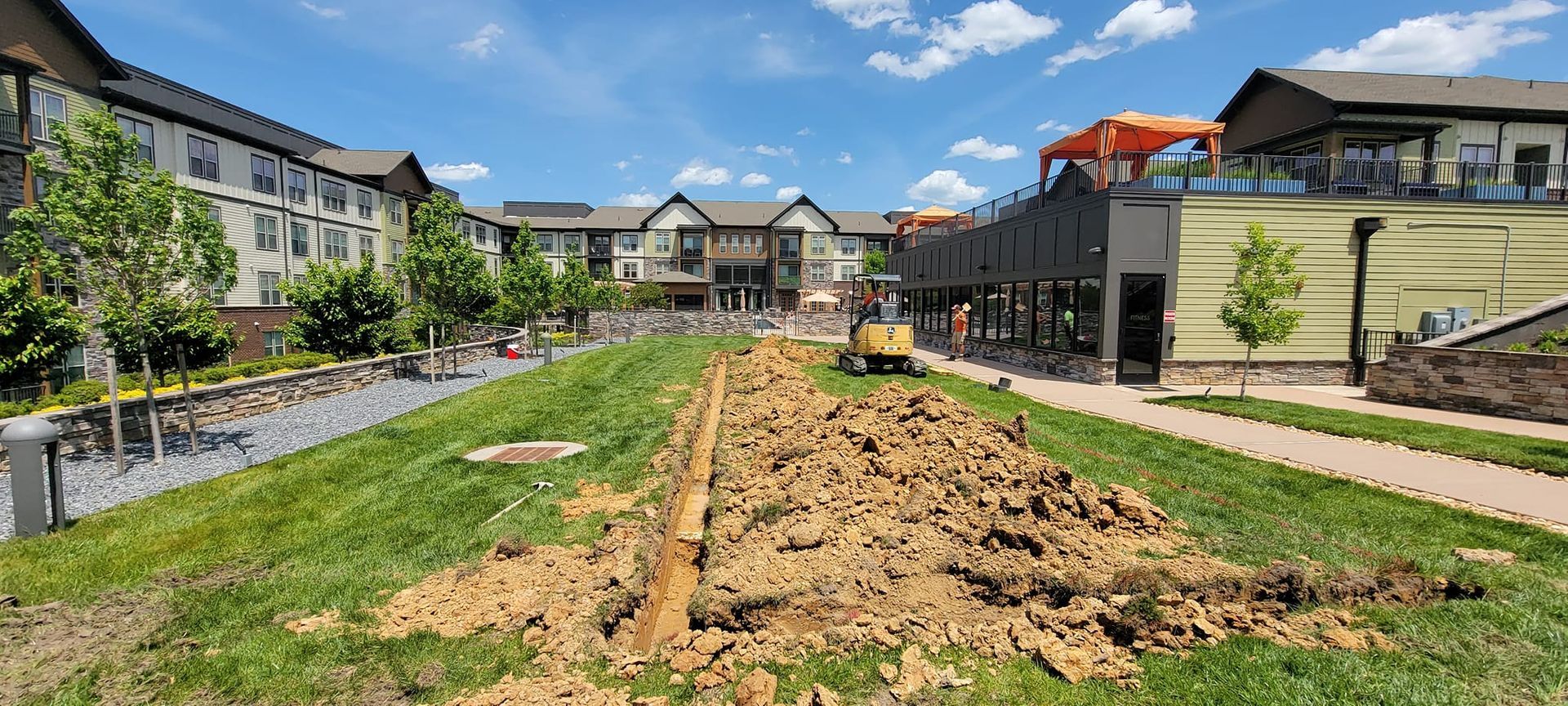 A large pile of dirt is sitting in the middle of a grassy field in front of a building.